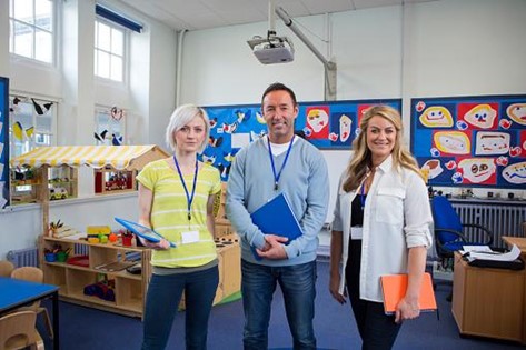 a small group of teachers smiling in a pre-school classroom